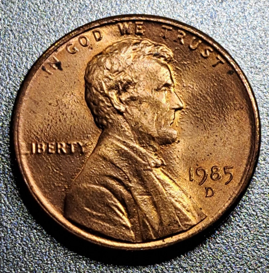 1985 penny broadstrike error showing wider diameter and missing rim compared to normal coin